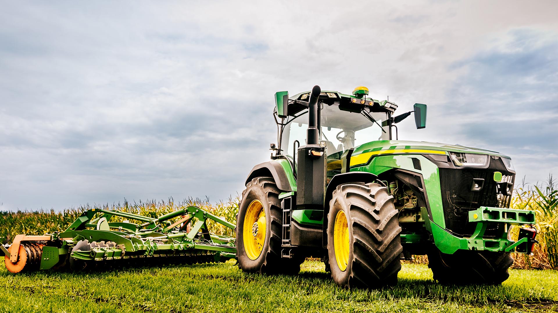 A modern green tractor, prepares agricultural land